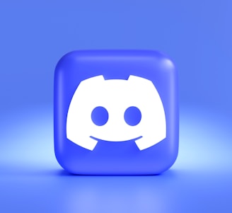 A three-dimensional blue cube featuring a white, stylized gaming controller symbol associated with a popular communication platform, set against a gradient blue background.
